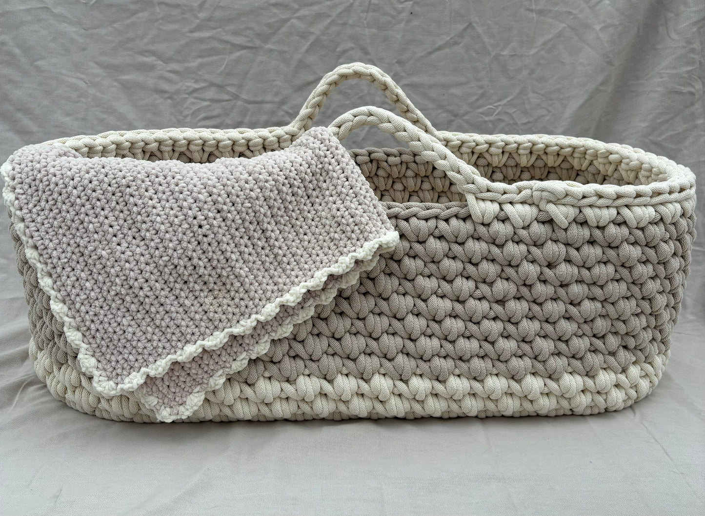 close up of beige moses basket with vanilla edging and the matching chunky blanket