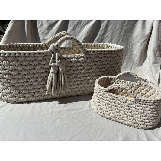 beige moses basket and nappy caddy side by side outside so you can see all the detail of the baskets and the crochet work