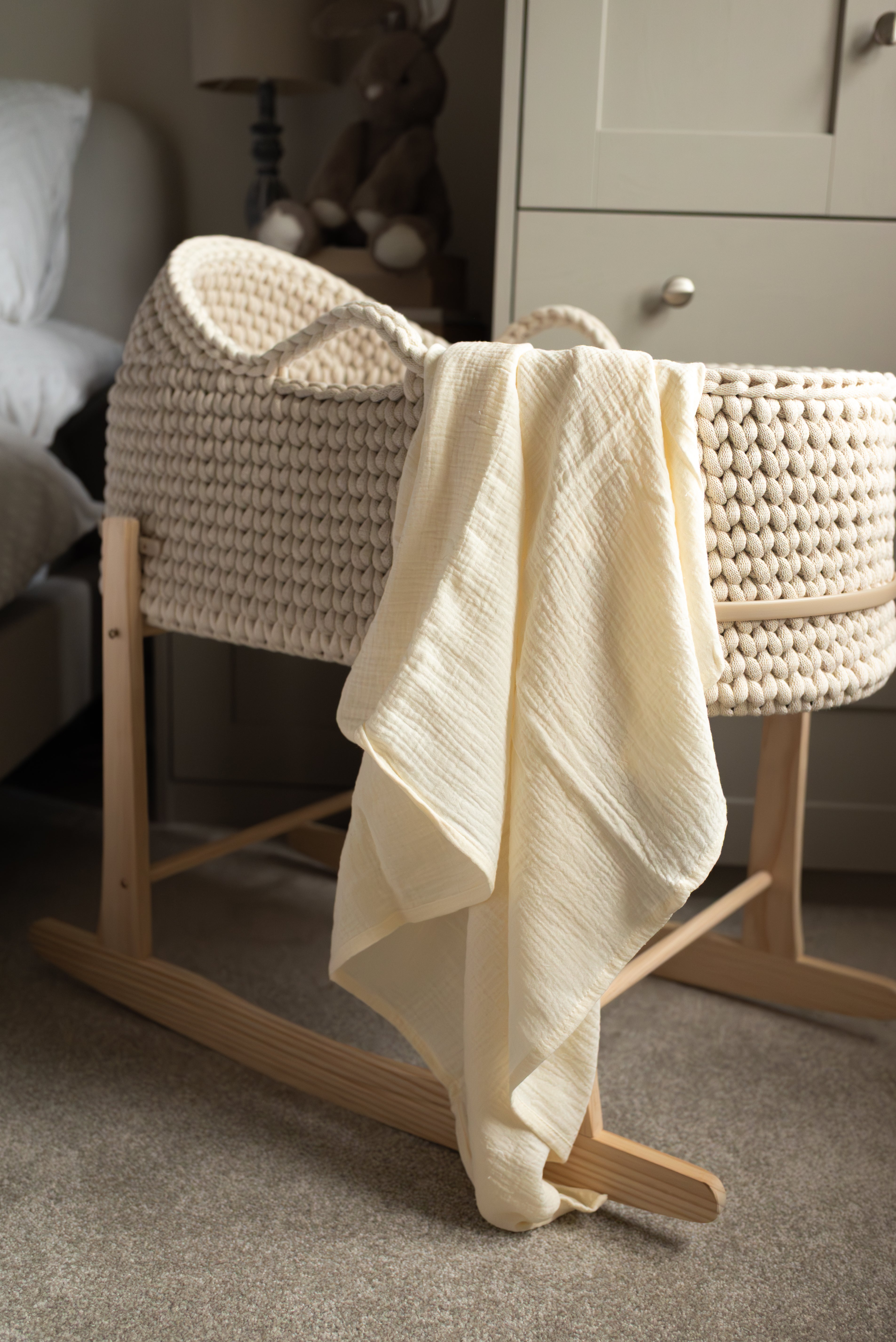 Wooden bassinet with textured cover and white blanket in a room setting