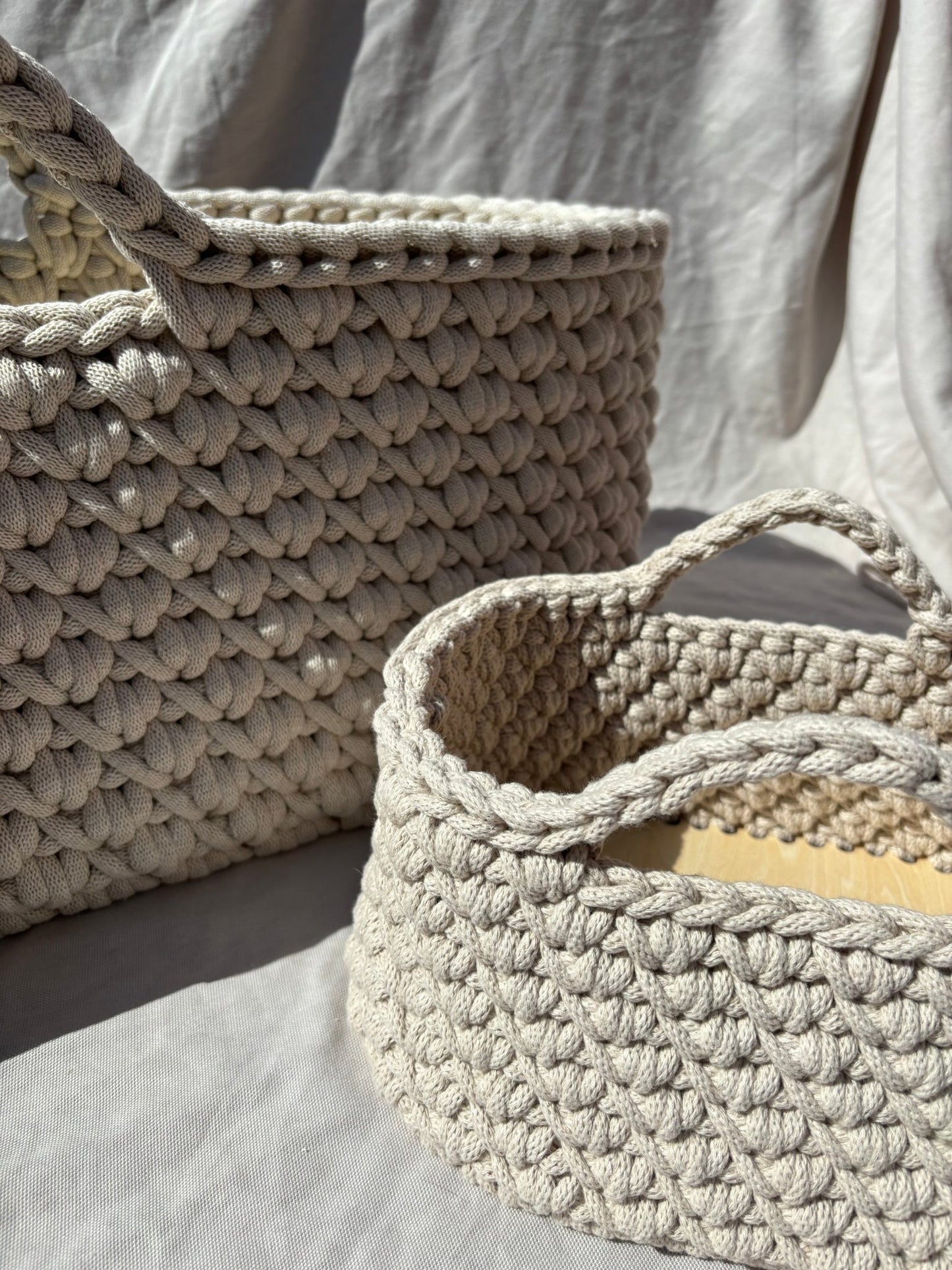 Two crochet baskets on a light gray surface