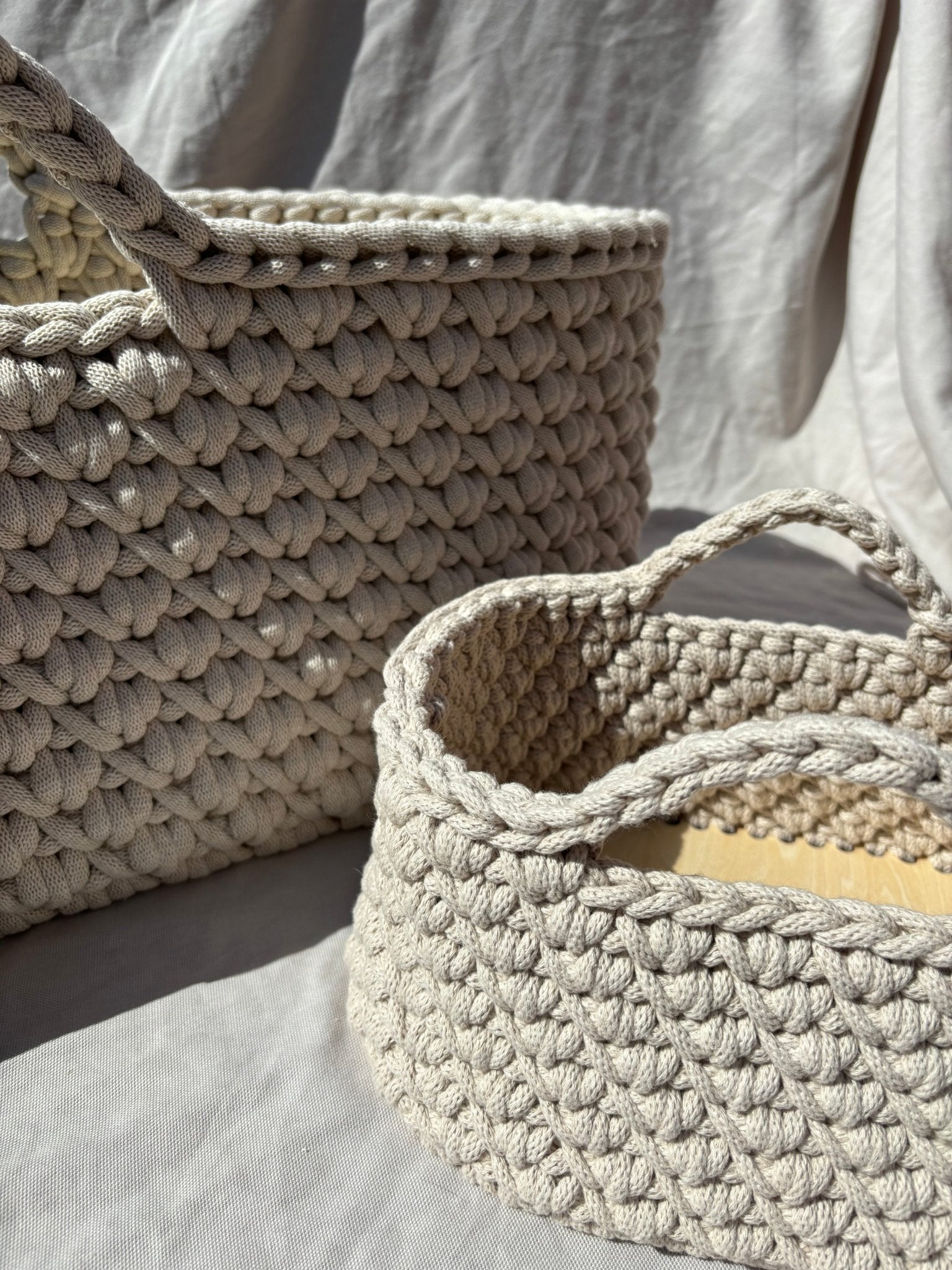 Two crochet baskets on a light gray surface