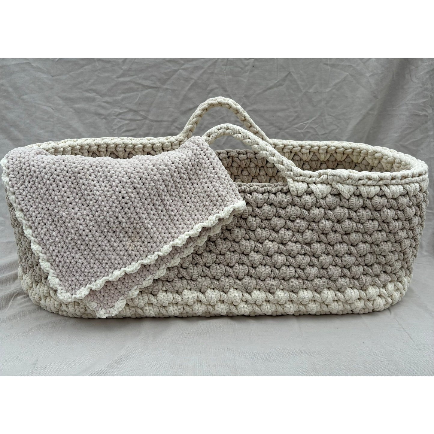 close up of beige moses basket with vanilla edging and the matching chunky blanket 